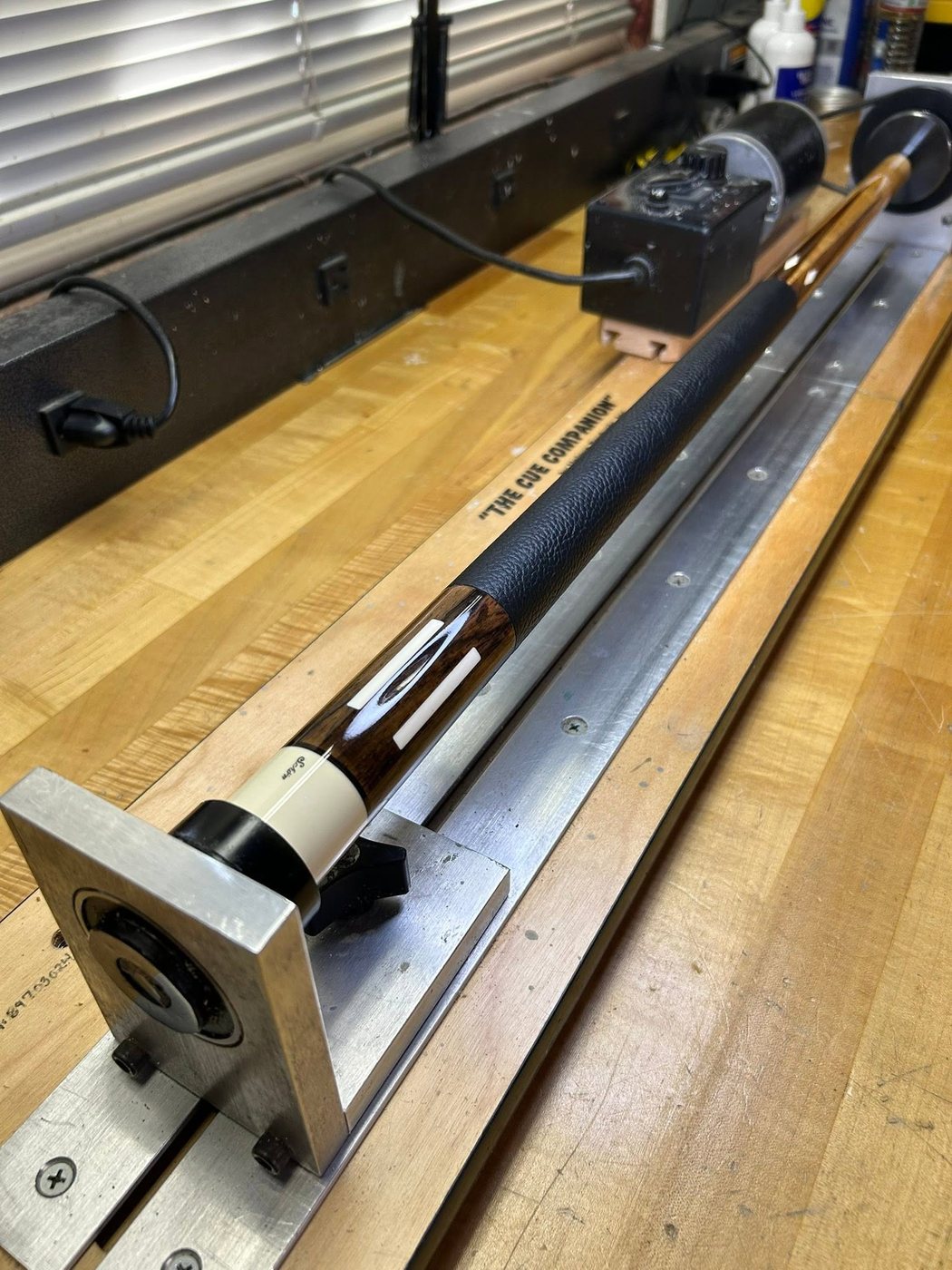 An inlaid cue clamped in the wrap machine, getting a fresh wrap installed